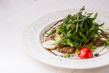 Salad with veal slices, arugula, tomatoes and eggs. over rustic