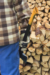 Partial picture of man with ax and chopped firewood. Outdoor in rain, backside, working clothes.