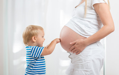 Little cute boy looking at mother pregnant tummy