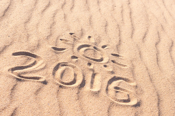 Sign 2016 and sun written on sandy beach. Summer travel concept