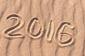 Sign 2016 and sun written on sandy beach. Summer travel concept