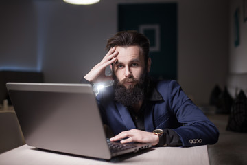 bearded man in suit and with laptop sitting in cafe and browsing