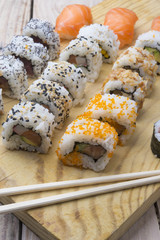 Different Sushi rolls,wasabi and ginger on a plate on wooden bac