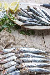 fresh sardines raw fish with coarse salt and thyme on brown pape