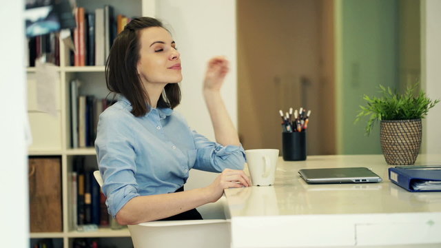 Young, beautiful businesswoman drinking coffee at home
