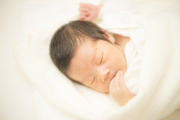 指をくわえて眠る新生児
