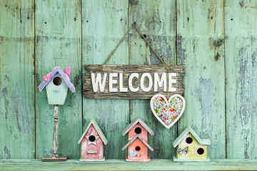 Welcome sign with heart hanging over colorful birdhouses