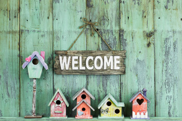 Welcome sign hanging over row of colorful spring birdhouses