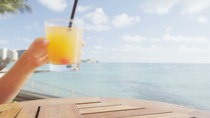 Alcoholic drinks - Beach bar party drinking friends toasting Hawaiian sunset cocktails having fun. Close up of woman holding alcoholic drink cheering in Waikiki beach, Honolulu, Oahu, Hawaii, USA.