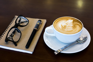 Coffee cup and notebook on table background.
