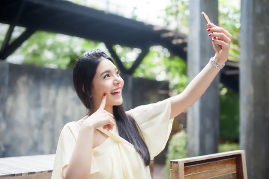 Asian Woman Taking A Selfie With Her Phone In Public Park