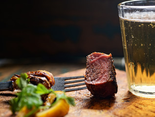 piece of steak on a fork with a beer