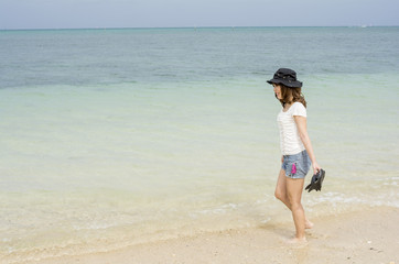 Fototapeta na wymiar 沖縄県恩納村の海辺に横向きで立つ女性