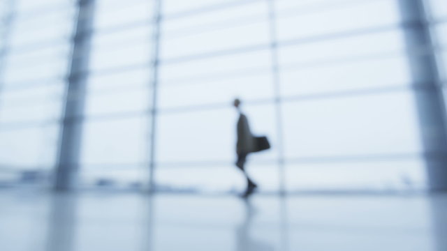 Man walking alone in office building in doubt regretting turning around walking away in solitude. Unrecognizable businessman out of focus and blurry walk. SLOW MOTION RED EPIC.