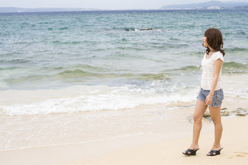 沖縄県恩納村の海辺に立つ女性