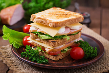 Club sandwich with cheese, cucumber, tomato, ham and eggs.