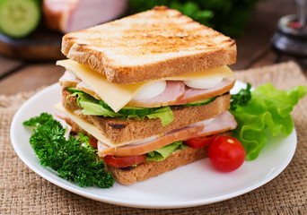 Club sandwich with cheese, cucumber, tomato, ham and eggs.