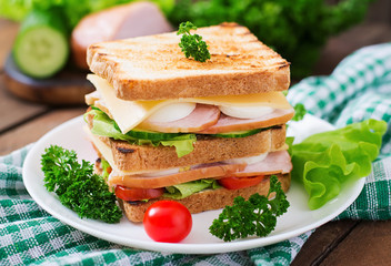 Club sandwich with cheese, cucumber, tomato, ham and eggs.