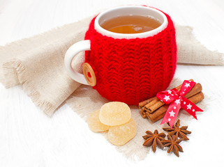 Чашка ароматного чая в вязаном  чехле и пряности
