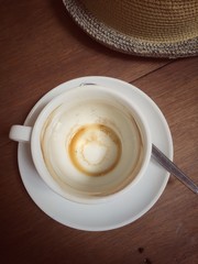 Empty coffee cup and part of weaving hat on wooden table, vintage effect