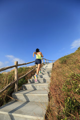 young fitness woman trail runner running up on mountain stairs