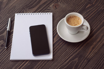 smartphone with open notebook and cup espresso