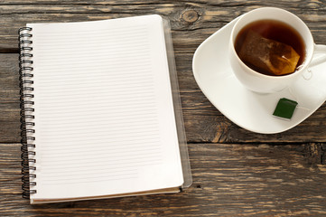open notebook with blank pages with cup of black tea