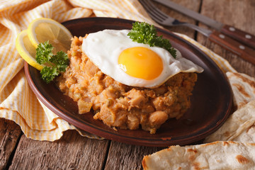 ful medames with a fried egg and pita close up. horizontal
