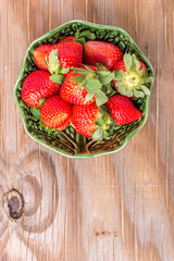 strawberries in a wooden bowl on the old wooden table