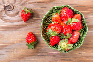 strawberries in a wooden bowl on the old wooden table