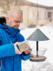 Man fills a bird feeder