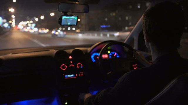 The man drive a car in the busy city. Inside view, left-hand traffic. Evening-night time, real time capture. Wide angle