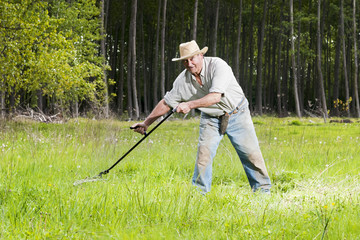  reaper man  with a scythe for mow the grass in the field