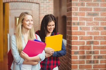 Smiling students with books in the hallway 