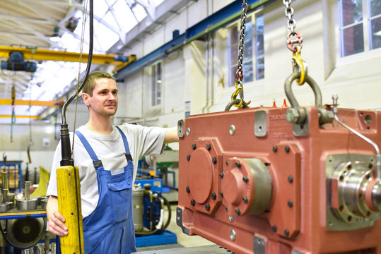 Monteur im Maschinenbau bedient Kran mit Werkstück zur weiteren Montage // industrial workers in mechanical engineering