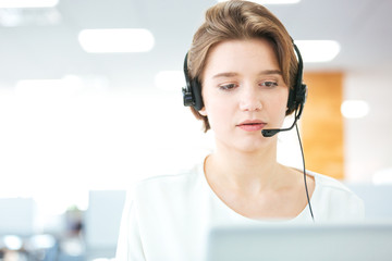 Serious pretty young woman working as support phone operator