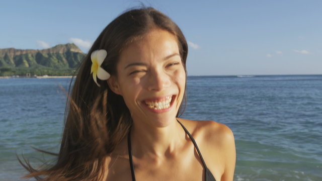 Beach woman smiling laughing having fun in bikini on Waikiki Hawaii. Hawaiian beach girl. beautiful biracial Asian Caucasian girl brunette having fun laughing and enjoying sunset. Oahu, Hawaii, USA