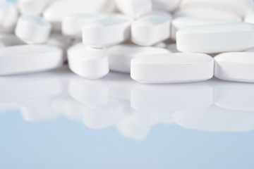 Heap of white pills close up on a blue