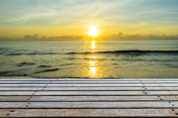 Fototapeta na wymiar Wood table top on blurred beach with sunrise background for presentation product.
