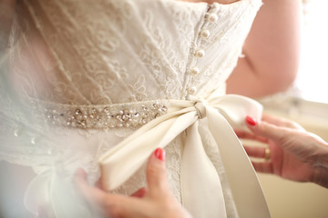 Bridesmaid helping bride teeing up her dress