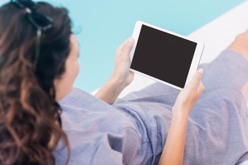 Young woman using digital tablet near poolside