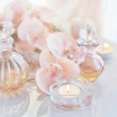 Perfume and aromatic oils bottles surrounded by flowers and cand