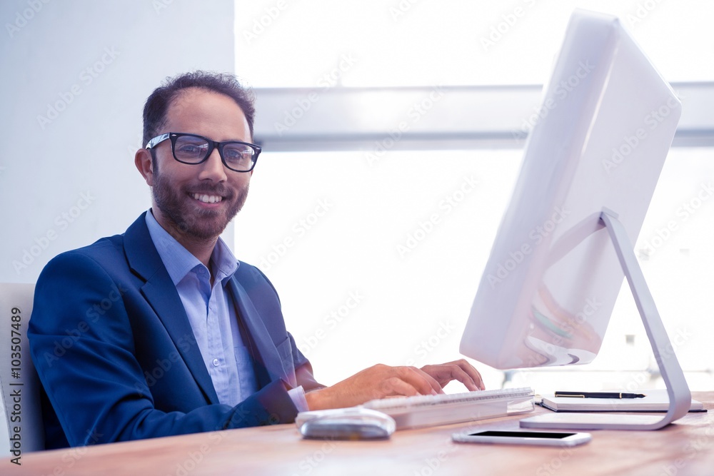 Poster portrait of happy businessman working on computer in office