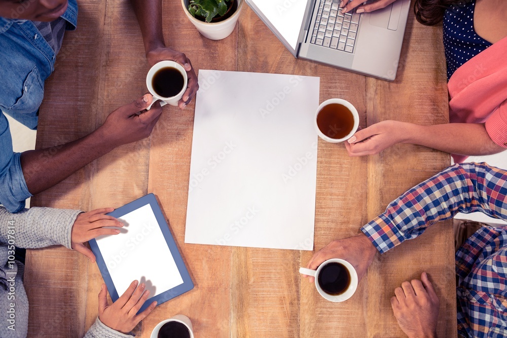 Poster professionals using technologies while holding coffee cups