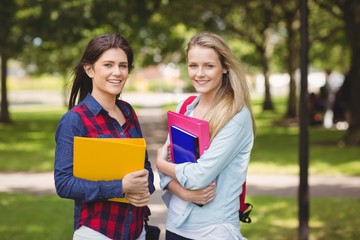 Smiling students holding binder 