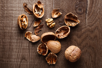 Whole and cracked walnuts on wooden background