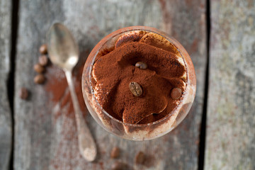 tiramisu in a vine glass on wooden surface