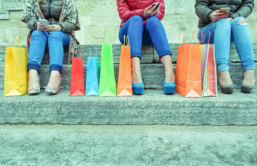 Happy young women with smartphones testing online after shopping