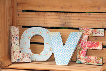 LOVE written with  colorful wooden letters decorated in decoupage technique posted on  wooden pallet - obrazy, fototapety, plakaty