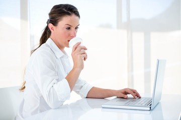 woman drinking a coffee and typing